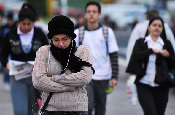 Mulher com roupas de frio andando na rua